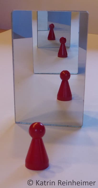 Reflexion einer Figur in einem Doppelpiegel.