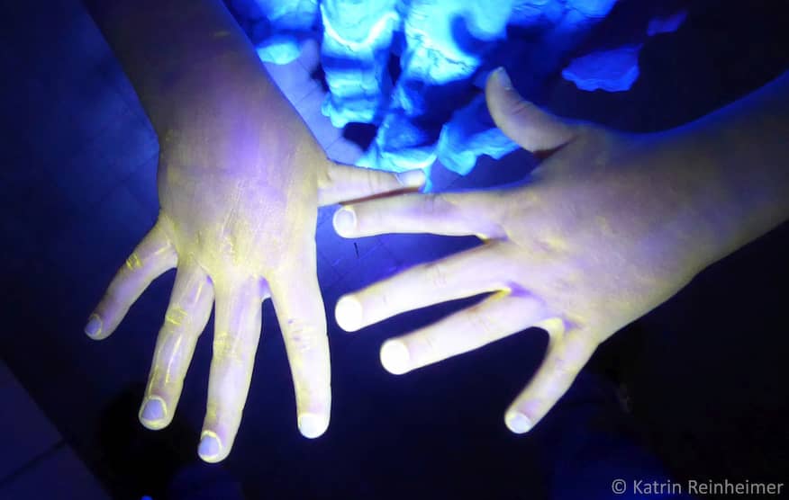 Mit UV-Creme eingecremte Hände unter UV-Licht.